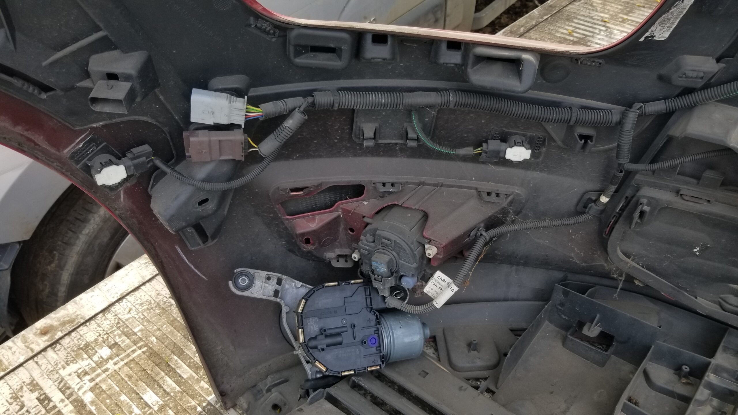 Close-up view of Citroën C4 Grand Picasso front bumper interior showing wiring harness, parking sensor, and motor assembly, genuine used part.