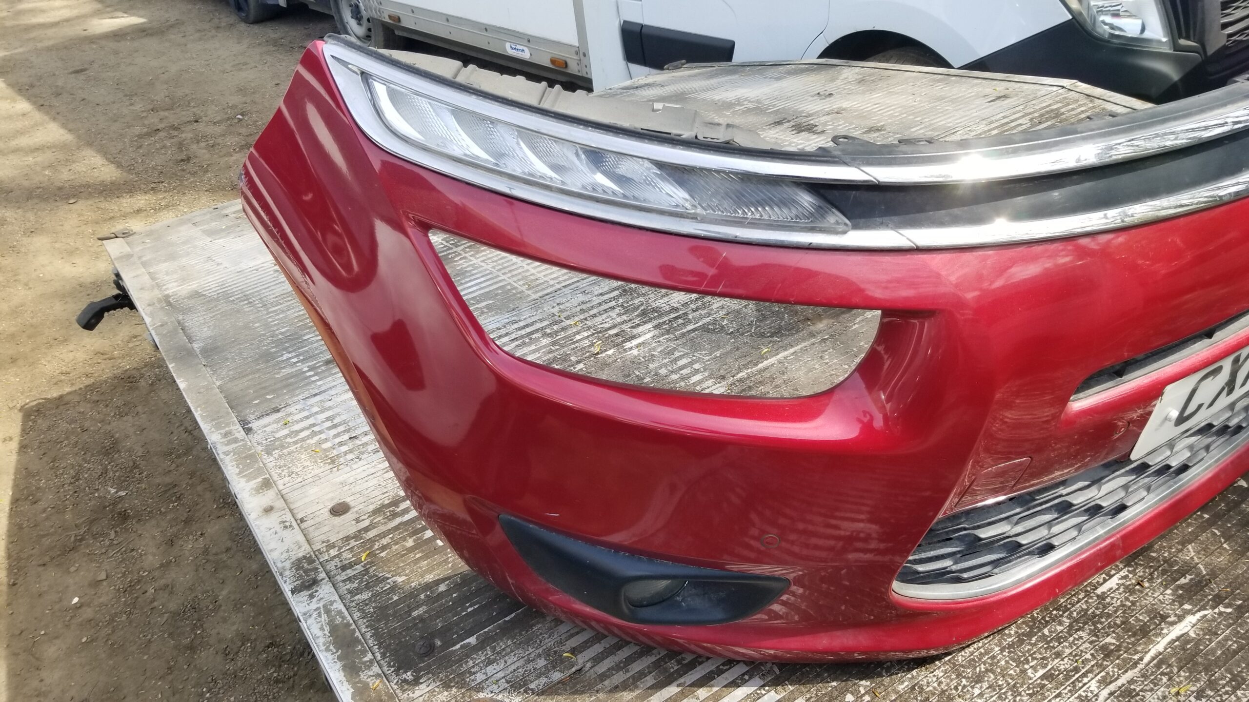 Right side view of used red front bumper for Citroën C4 Picasso 2015 – with fog light and trim