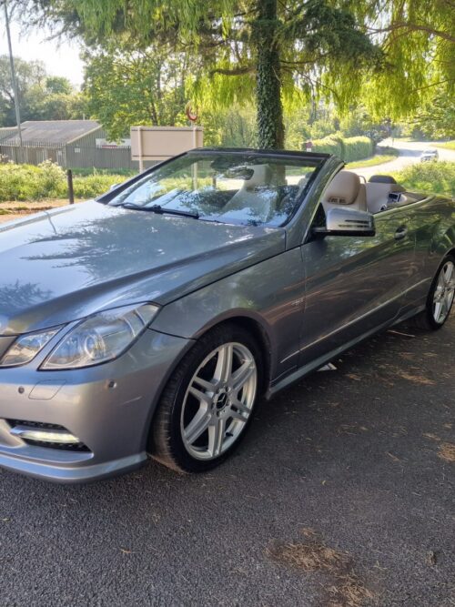 Front-side view of a 2012 Mercedes-Benz E-Class E220 Cabriolet in metallic silver with alloy wheels and beige leather interior, available for sale in the UK