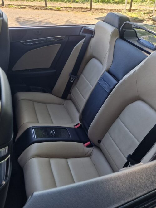 Rear passenger seats of a 2012 Mercedes-Benz E-Class E250 Cabriolet with beige leather upholstery and integrated armrest