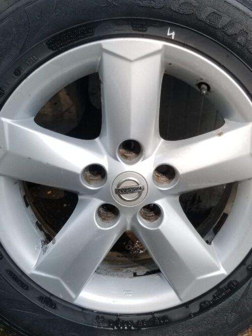 Close-up of wheel face showing Nissan badge and finish