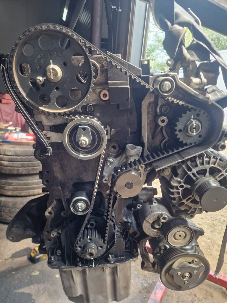 Close-up of a VW Crafter engine showing timing belt kit alignment with pulleys and tensioners during engine assembly